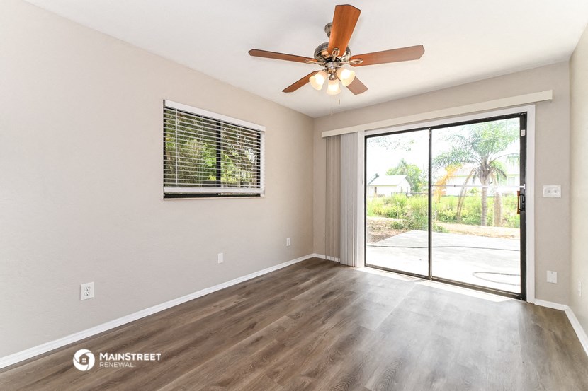 an empty living room with a ceiling fan and a sliding glass door
