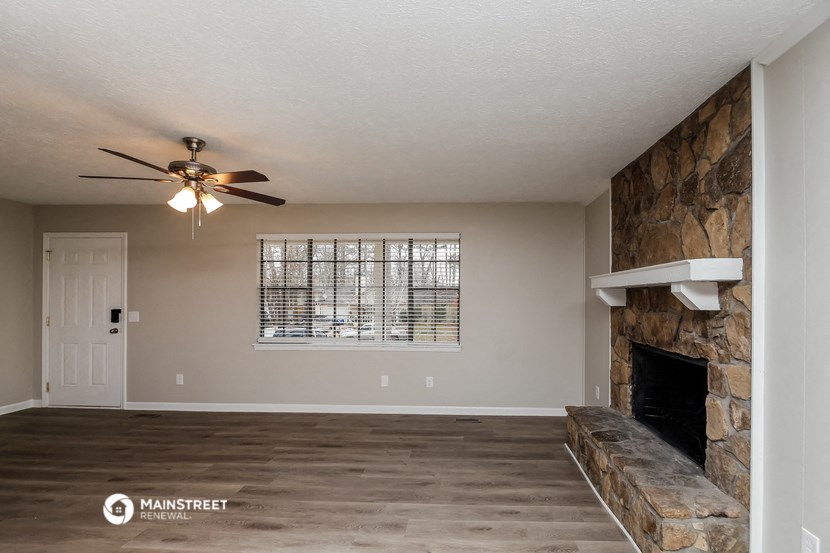 a living room with a fireplace and a ceiling fan