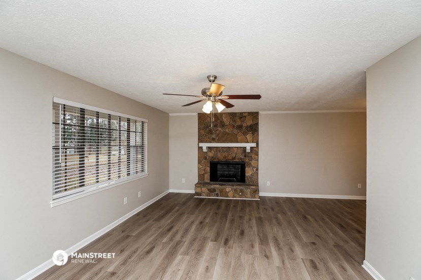 an empty living room with a fireplace and a ceiling fan