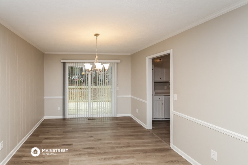 an empty living room with a door to the kitchen