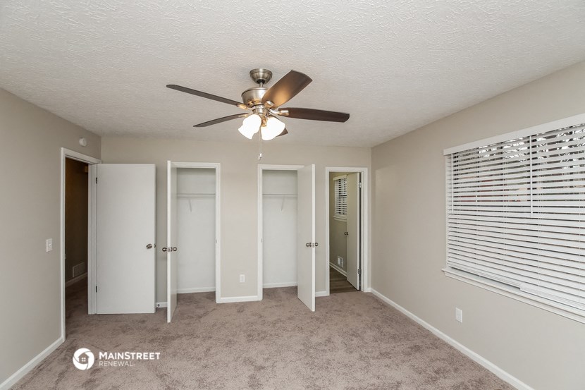 a bedroom with a ceiling fan and a door to a closet