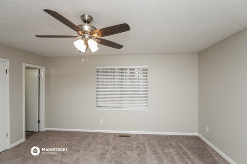 the spacious living room with ceiling fan and carpet