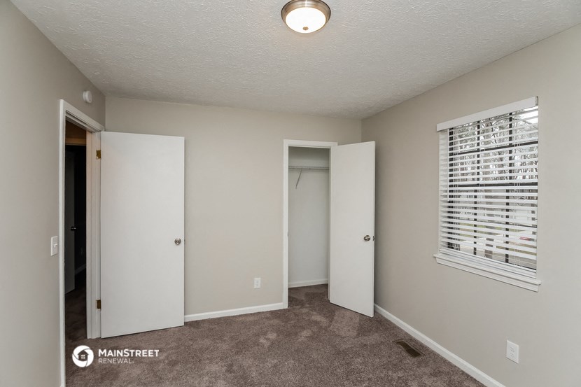 a bedroom with a door to a closet and a window