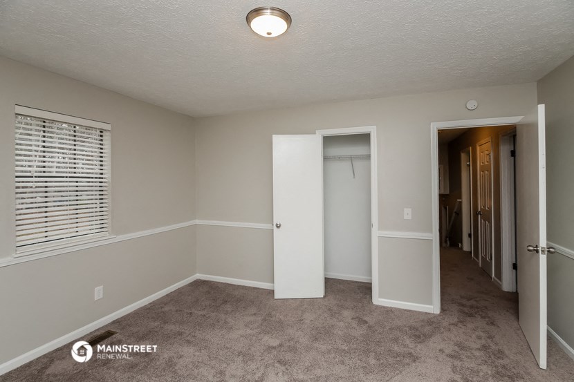 an empty room with a door to a closet and a window