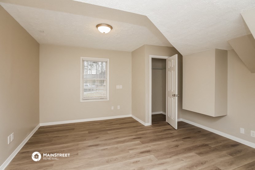 the spacious living room with a door to the closet and a window