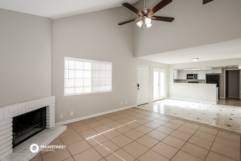 an empty living room with a fireplace and a ceiling fan