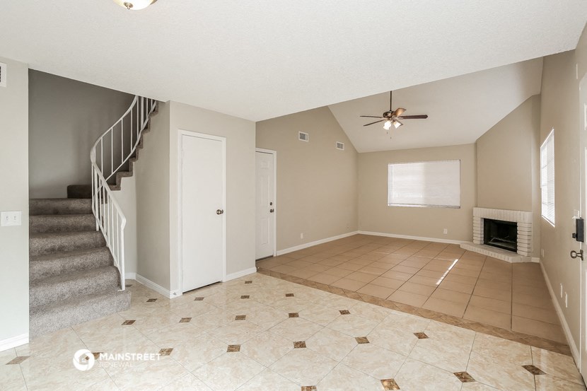 an empty living room with a fireplace and a ceiling fan