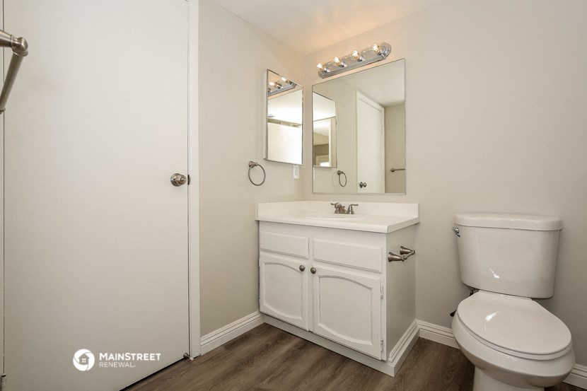 a white bathroom with a toilet sink and mirror