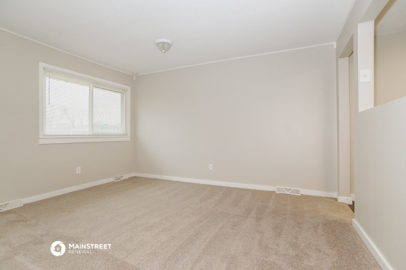 the spacious living room with carpeting and a large window
