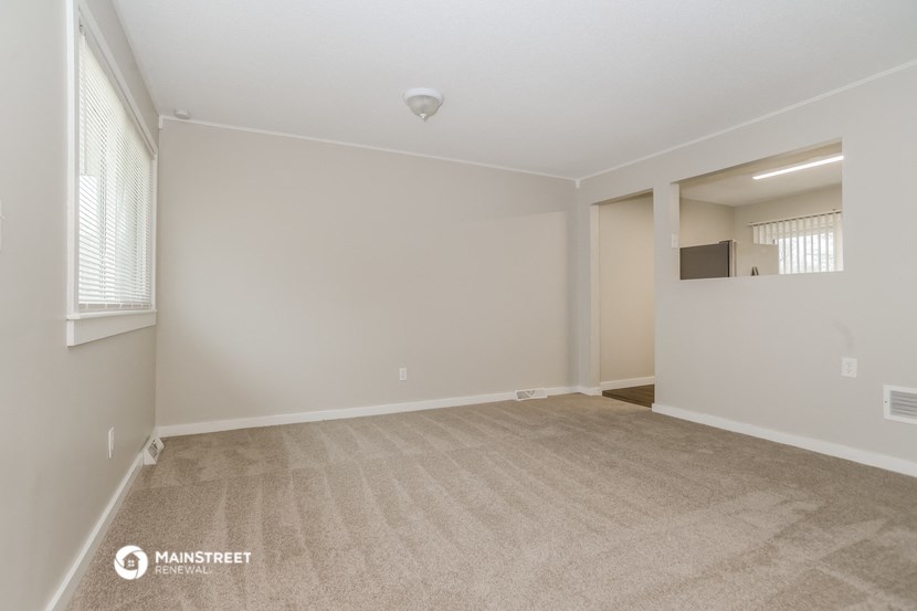 the spacious living room with carpet and white walls