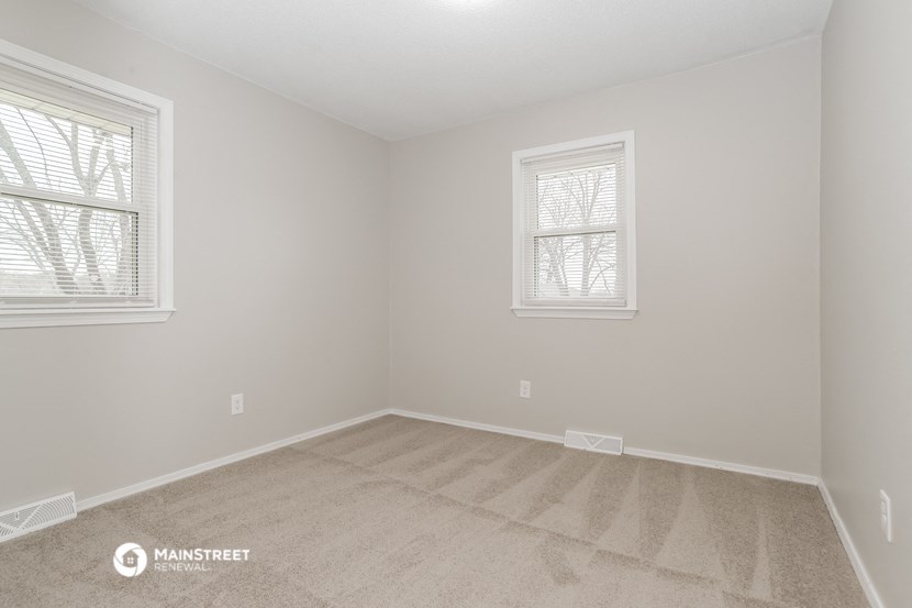 a bedroom with two windows and a carpeted floor