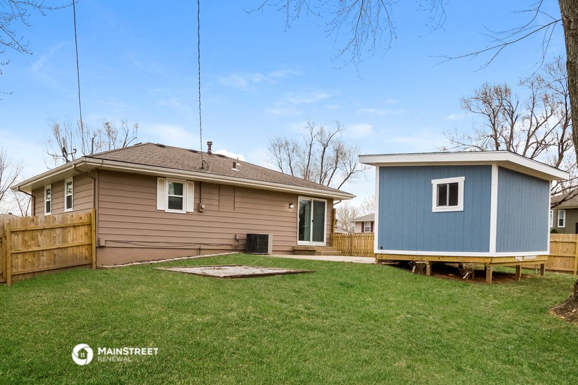 a home with a blue shed and a brown house on a lawn