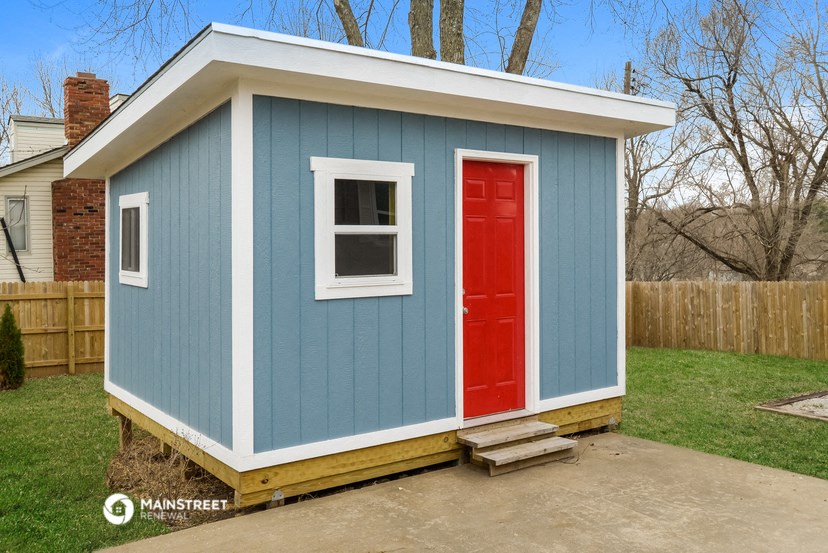 a blue tiny house with a red door and window