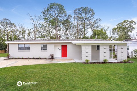 a small white house with a red door and a lawn
