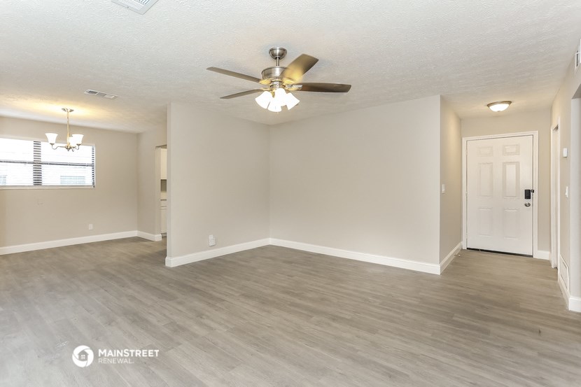 the living room and dining room of an empty home with a ceiling fan