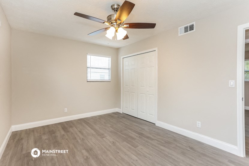 the spacious living room with ceiling fan and closet