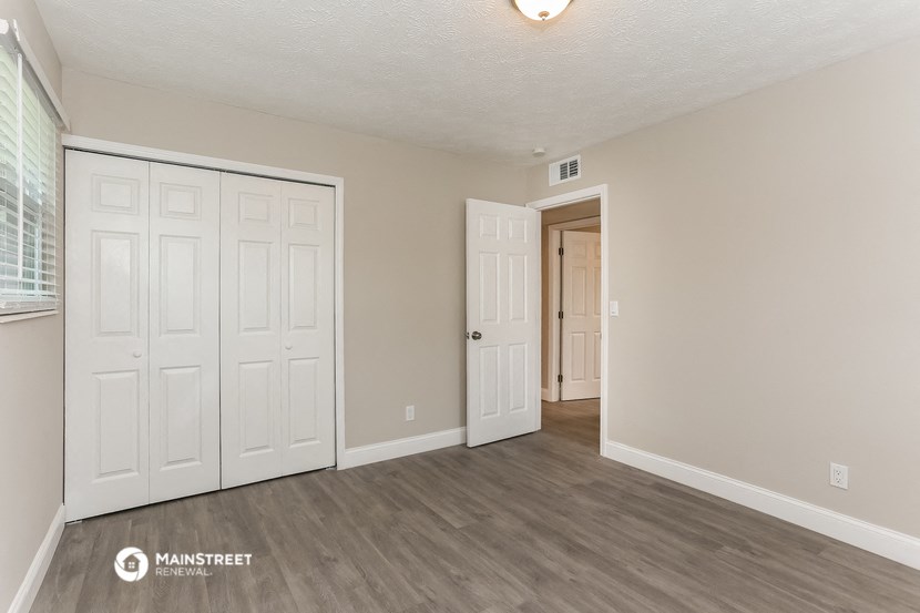 the living room of an apartment with white doors and a door to the hallway