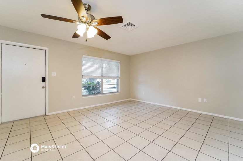 an empty living room with a ceiling fan and tiled floor