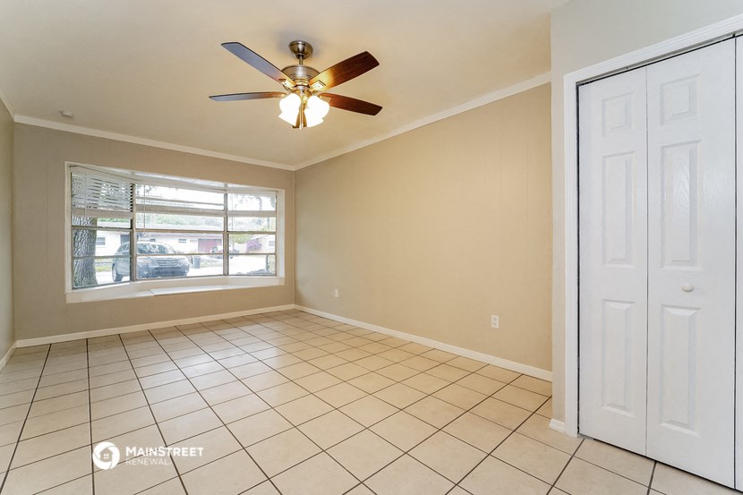 an empty living room with a ceiling fan and a window