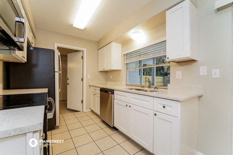 a kitchen with white cabinets and a sink and a window