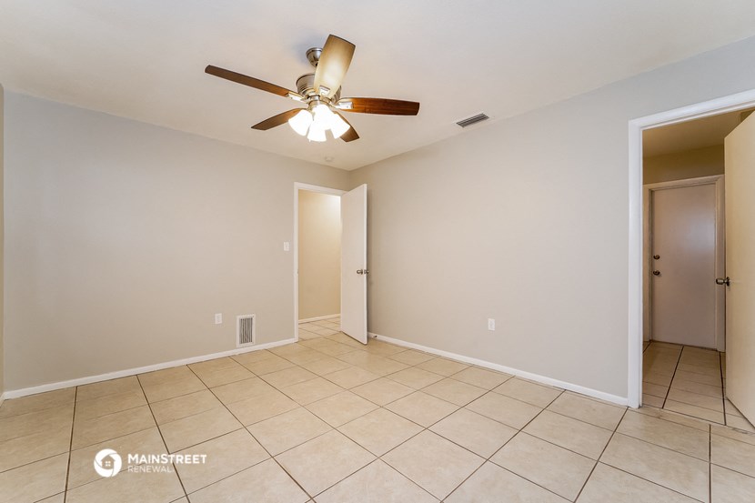 the living room and dining room with ceiling fan and tiled floor