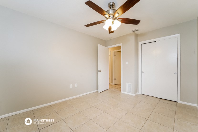 a living room with a ceiling fan and a door to a hallway