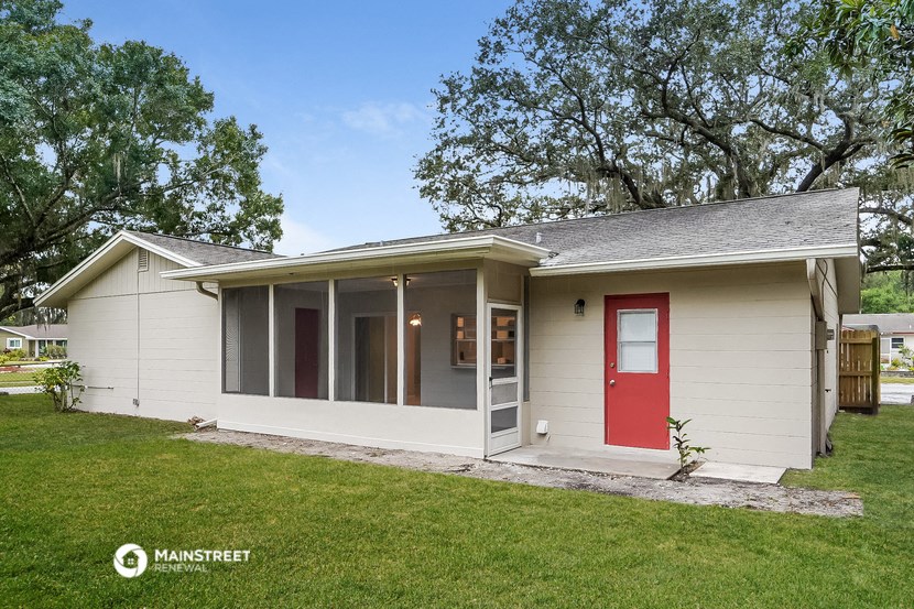the front of a white house with a red door