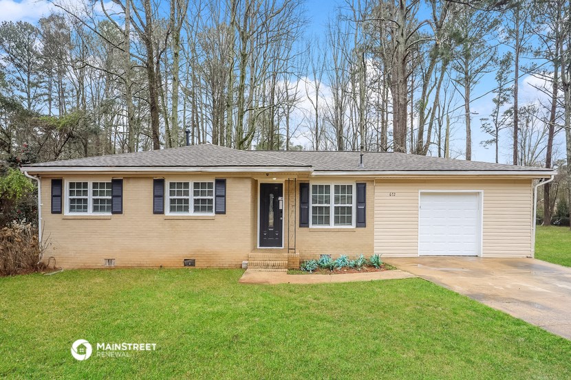 a yellow house with black shutters and a lawn