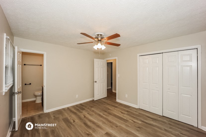 a living room with a ceiling fan and a door to a bathroom