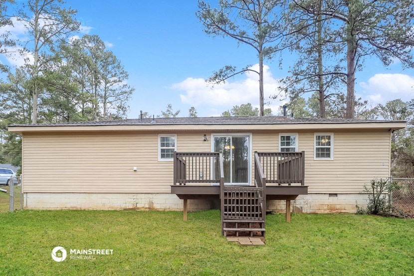 a yellow house with a deck and a front yard