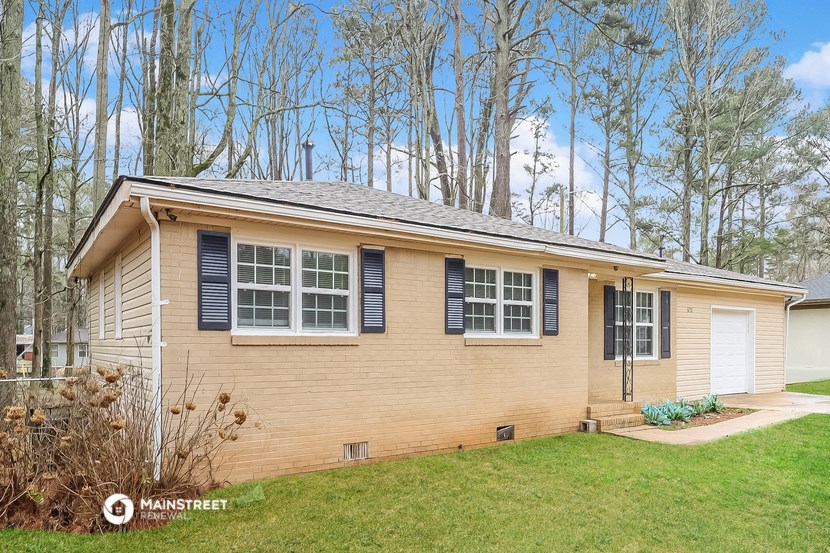 a small yellow house with black shutters and a lawn