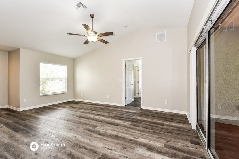 the living room of an empty house with a ceiling fan