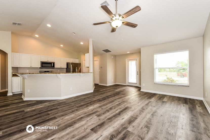 a living room with a kitchen and a ceiling fan