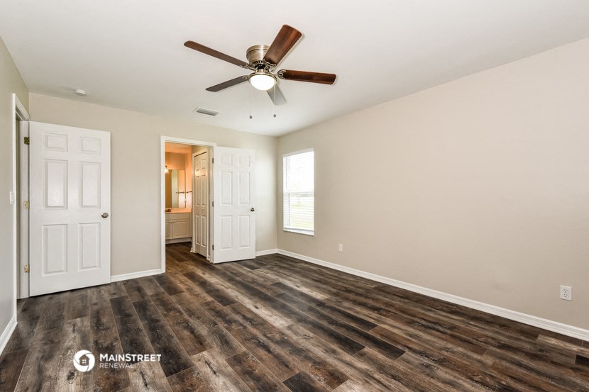 the living room is spacious and has a ceiling fan