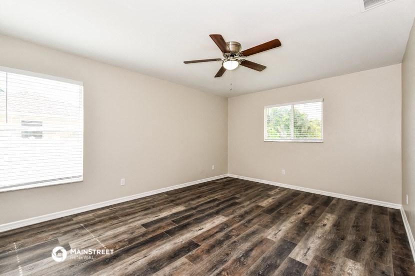 the spacious living room with hardwood floors and a ceiling fan