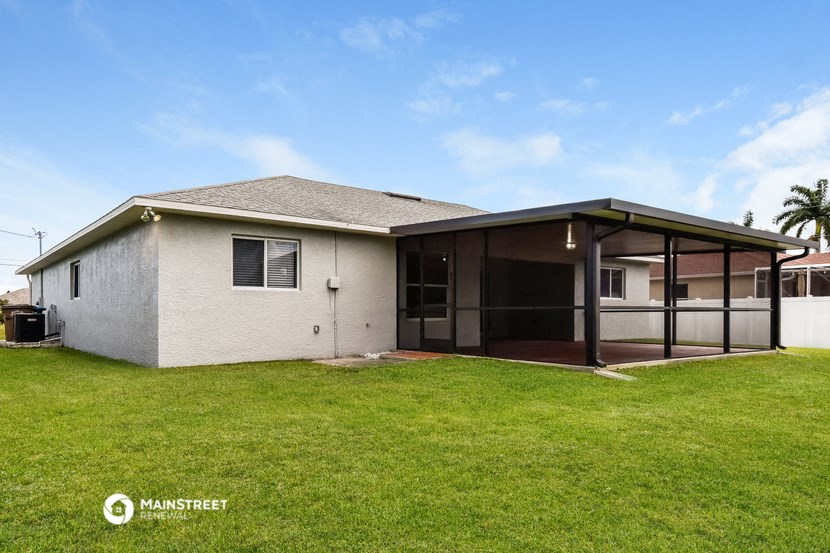 a white house with a grass yard and a covered patio