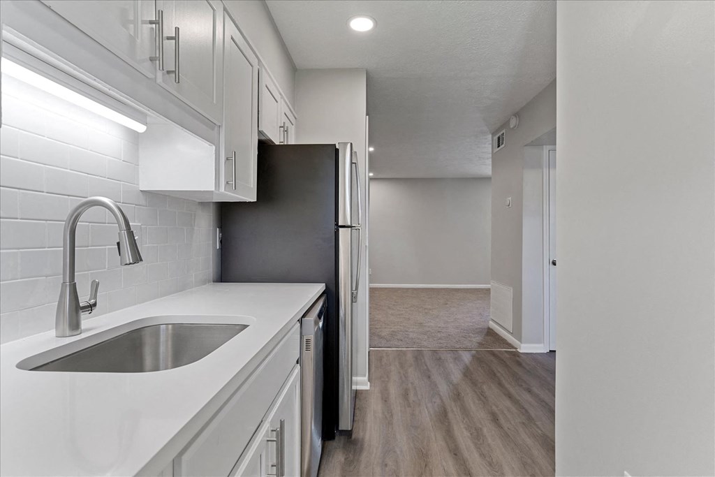 A kitchen with a black refrigerator and white cabinets.