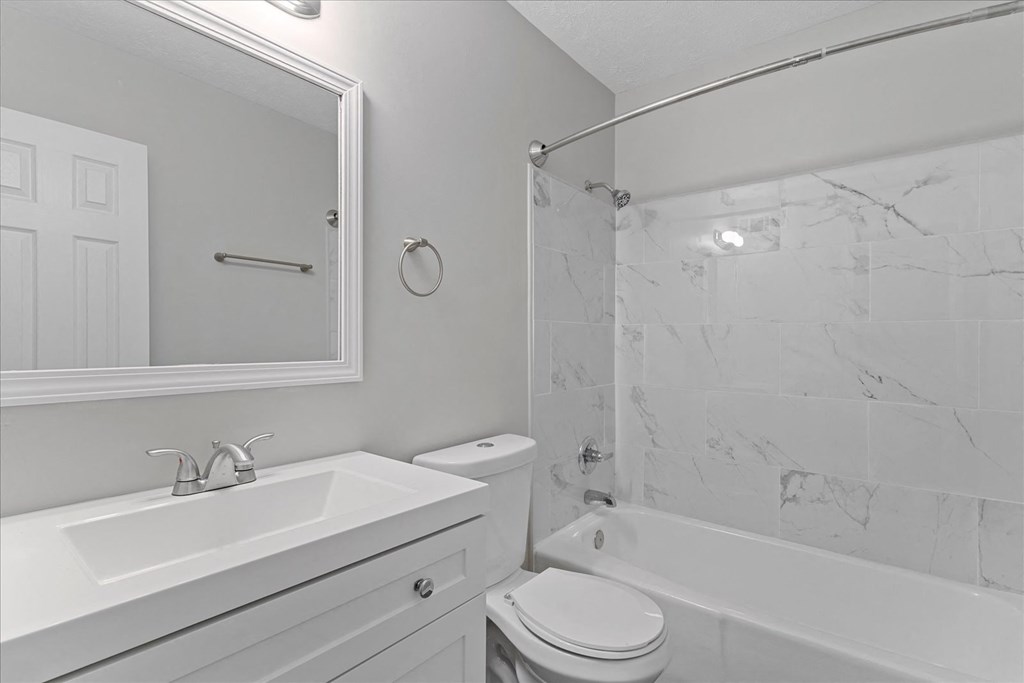 A white bathroom with a marble tile shower.