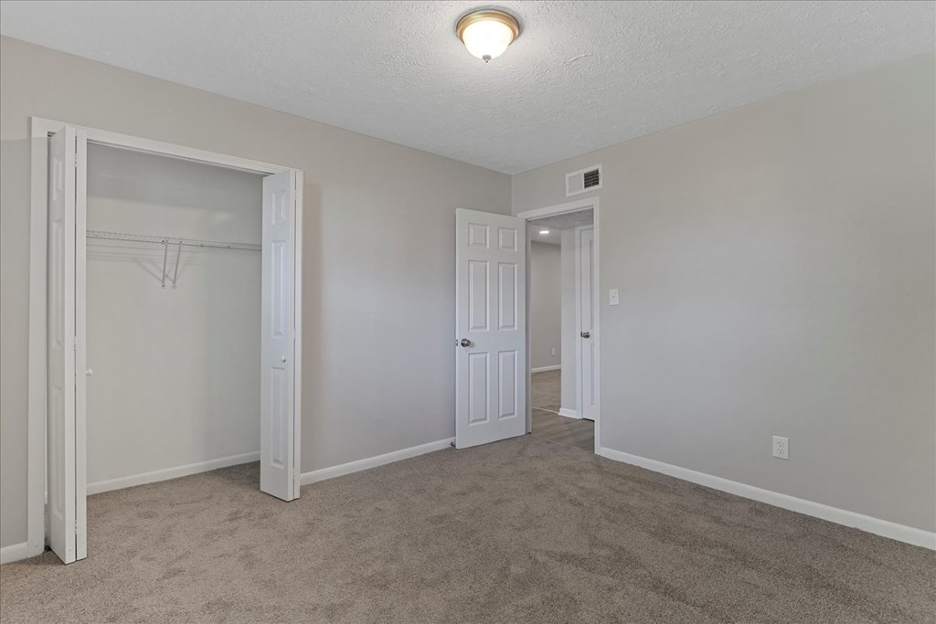 A room with a carpeted floor and two doors.
