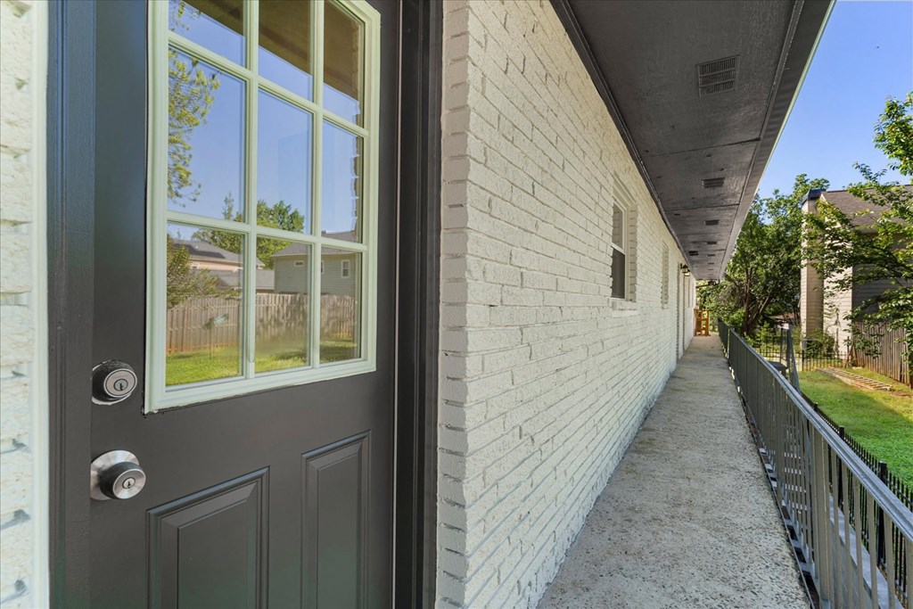 A grey door with a glass window is on the left and a white wall is on the right.