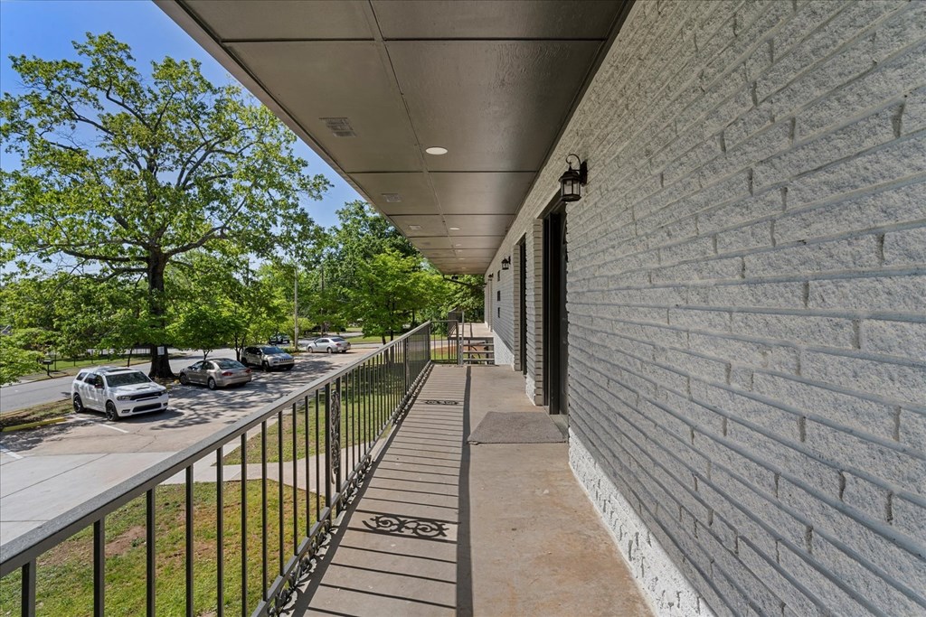 A long concrete walkway with a metal railing and a brick wall on one side.