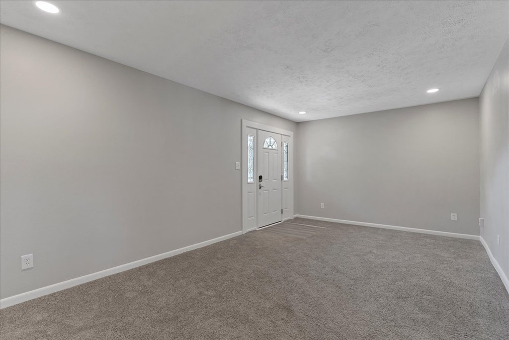 A room with a carpeted floor and a white door.