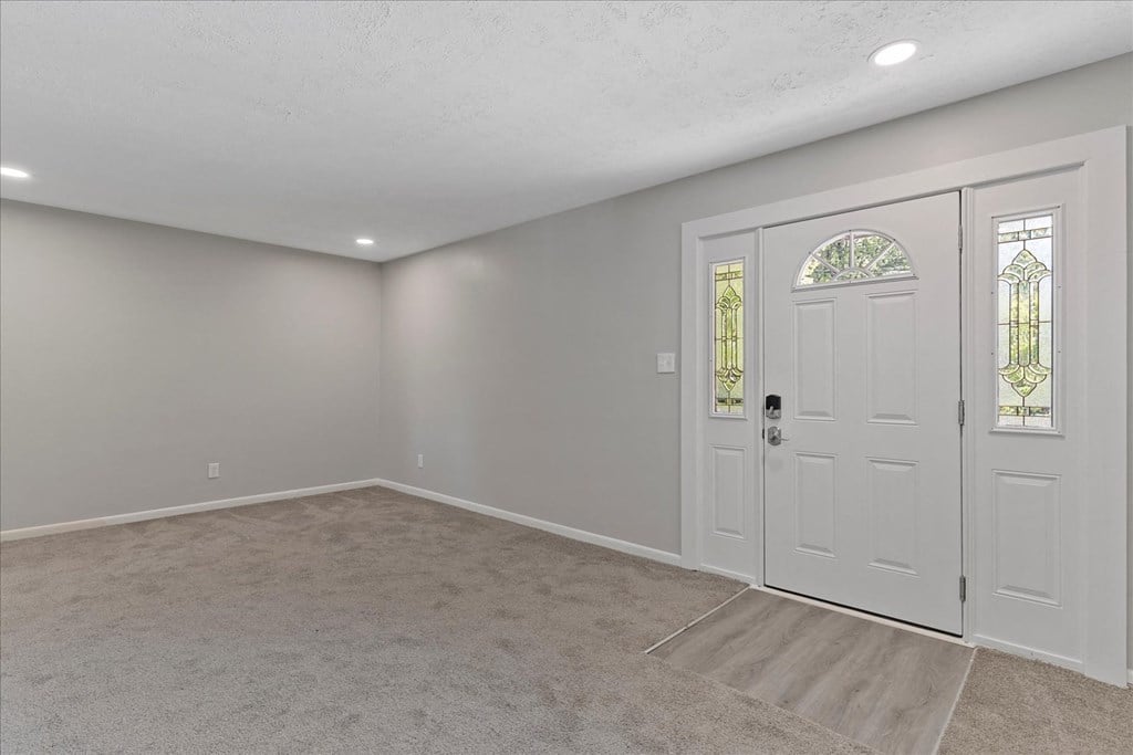 A room with a white door and a carpeted floor.