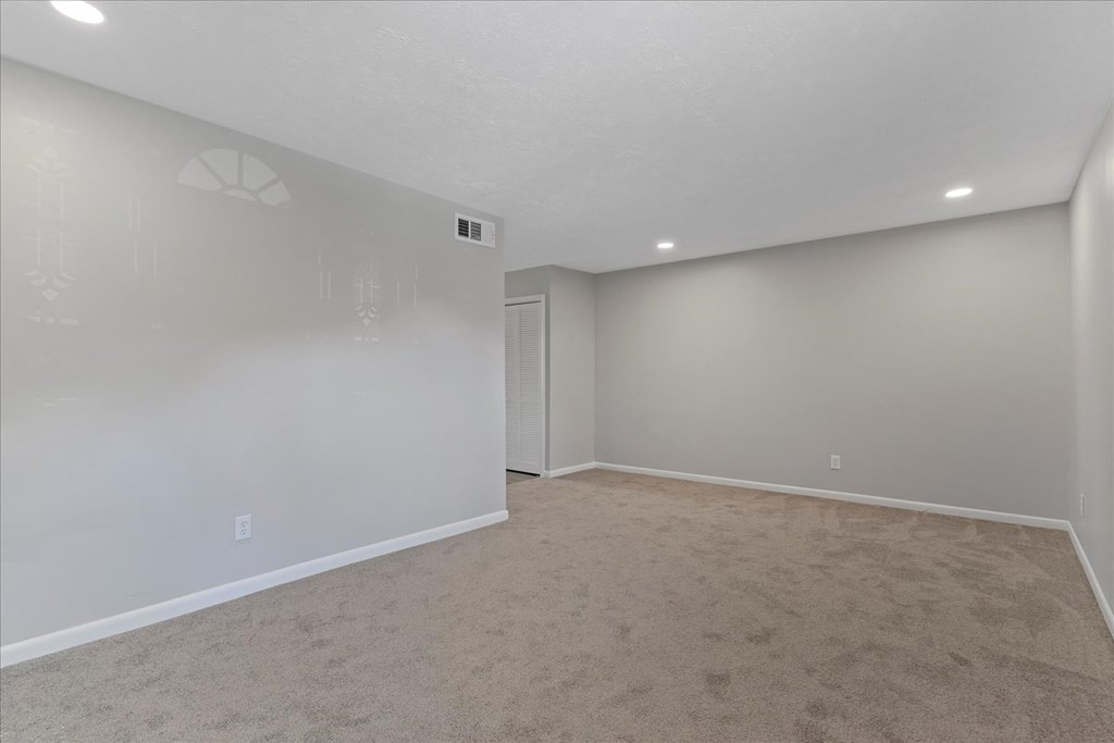 A spacious room with carpeted floor and white walls.