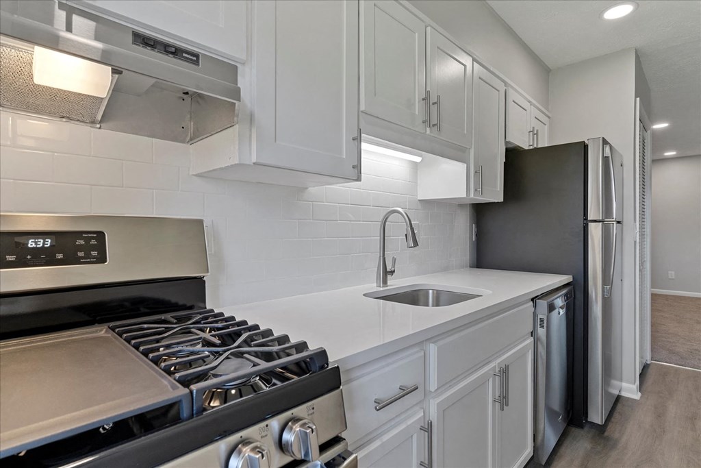 A modern kitchen with a stove, sink, and refrigerator.