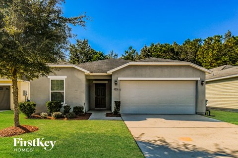 A house with a garage door and a tree in front of it.