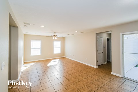 A spacious room with tile flooring and a chandelier hanging from the ceiling.