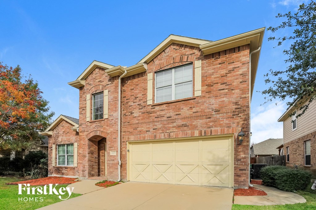 A brick house with a garage door in the foreground.