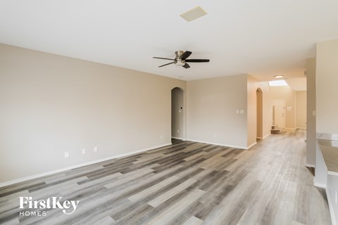 A spacious room with wooden flooring and a ceiling fan.