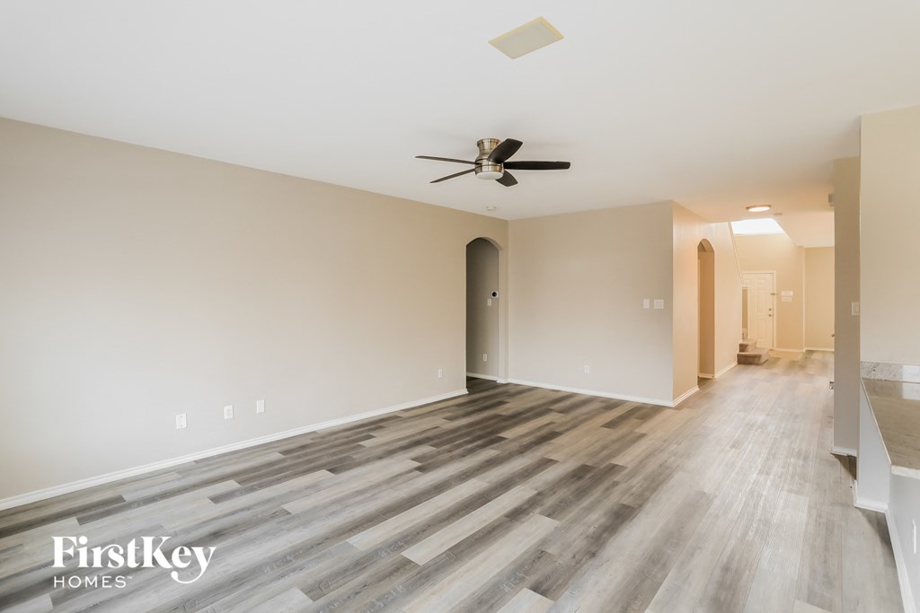 A spacious room with wooden flooring and a ceiling fan.